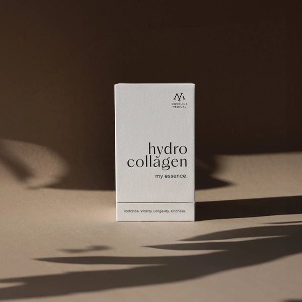 A high-quality studio shot of a white collagen product box placed on a neutral background with soft, artistic shadows.